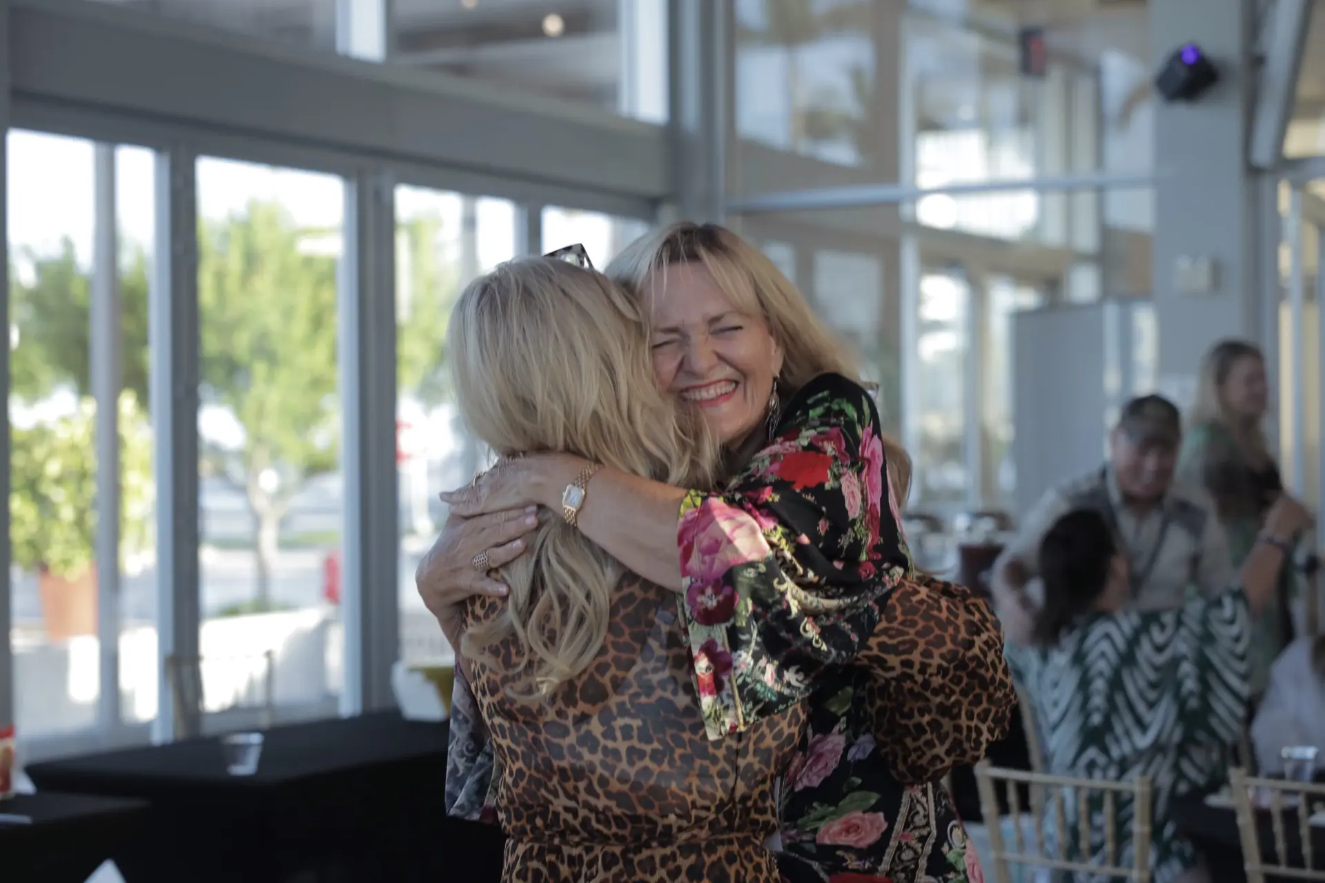 Two members of a Happiness Circle gathering embracing and laughing